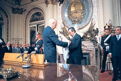 El presidente de facto Reynaldo Benito Antonio Bignone le entrega la banda y el bastón a Raúl Alfonsín el 10 de diciembre de 1983 en la Casa Rosada