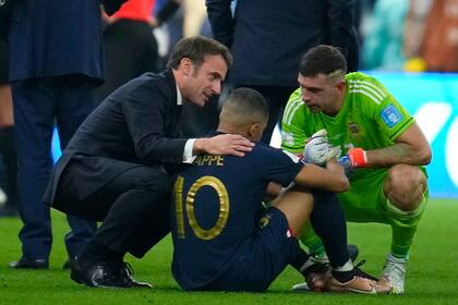 El presidente de Francia Emmanuel Macron y Emiliano Martínez, arquero de Argentina, consuelan a Kylian Mbappe tras la derrota gala