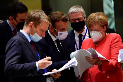 El presidente del Gobierno de España, Pedro Sánchez, el presidente francés Emmanuel Macron y la canciller alemana Angela Merkel examinan los documentos durante una cumbre de la UE en Bruselas el 20 de julio de 2020
