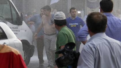 El presidente del Partido Liberal, Efraín Alegre, camina entre agua lanzada por policías paraguayos para disolver una protesta hoy.