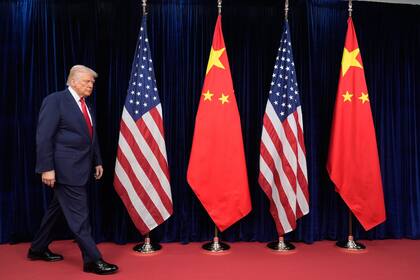 El presidente Donald Trump camina frente a las banderas de Estados Unidos y China para reunirse con el presidente chino, Xi Jinping, en el Aeropuerto Internacional de Gimhae, en Busan, Corea del Sur, el jueves 30 de octubre de 2025