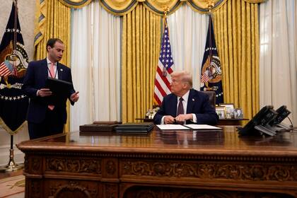 El presidente Donald Trump habla con Will Scharf, secretario de personal de la Casa Blanca, mientras firma órdenes ejecutivas en la Oficina Oval de la Casa Blanca, el jueves 23 de enero de 2025, en Washington. (AP Foto/Ben Curtis)