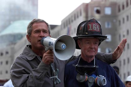 El presidente estadounidense George W. Bush (izq.) Habla junto al bombero retirado Bob beckwith, de 69 años, a voluntarios y bomberos mientras examina los daños en el sitio del World Trade Centerl el 14 de septiembre de 2001 en Nueva York