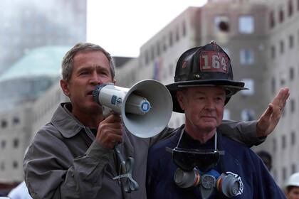 El presidente estadounidense George W. Bush, junto al bombero retirado Bob beckwith de 69 años, habla a voluntarios y bomberos el 14 de septiembre de 2001