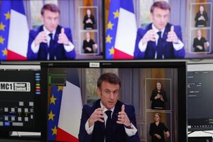 El presidente francés Emmanuel Macron aparece en las pantallas mientras habla durante una entrevista televisiva desde el Palacio del Elíseo, en París, el 22 de marzo de 2023.