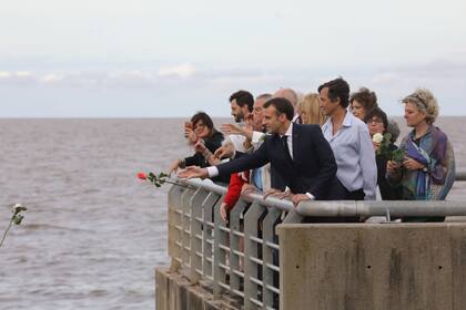 El presidente francés, Emmanuel Macron, arroja flores al río en el Parque de la Memoria