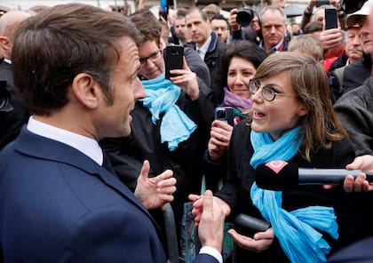 El presidente francés, Emmanuel Macron, habla con una persona que se opone a la reforma de las pensiones, en Selestat, este de Francia, el 19 de abril de 2023.