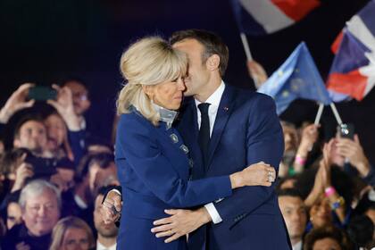 El presidente francés y candidato del partido La Republique en Marche (LREM) a la reelección, Emmanuel Macron, y su esposa Brigitte Macron celebran tras su victoria en las elecciones presidenciales de Francia, en el Campo de Marte de París, el 24 de abril de 2022.