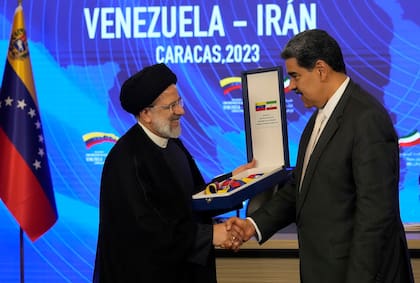 El presidente iraní, Ebrahim Raisi, estrecha la mano del presidente venezolano, Nicolás Maduro, al recibir la Orden del Libertador y Libertadora de Primera Clase, en el palacio presidencial de Miraflores, en Caracas, Venezuela, el lunes 12 de junio de 2023