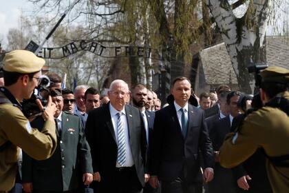 El presidente polaco Andrzej Duda y su par israelí Reiven Rivlin caminan delante del famoso letrero de entrada "Arbeit macht frei" (El trabajo te libera)