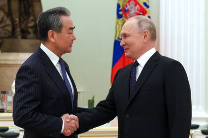 El presidente ruso Vladimir Putin saluda al canciller chino Wang Yi