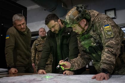 El presidente ucraniano Volodymyr Zelenskyy, el comandante de las fuerzas de tierra, coronel general Oleksandr Syrsky, derecha, y el subjefe de la oficina presidencial Roman Mashovets, estudian un mapa durante su visita a la ciudad de Kupiansk, región de Járkov, en el frente de la guerra de Ucrania, 30 de noviembre de 2023. Zelenskyy dice que la guerra con Rusia ha entrado en una nueva etapa ante la inminencia del invierno. (AP Foto/Efrem Lukatsky)