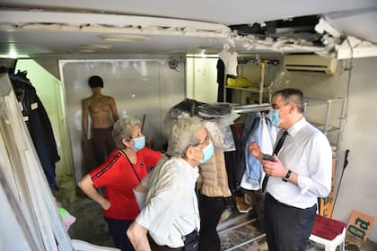 El primer ministro del Líbano, Mustapha Adib (derecha), habla con los propietarios de una tienda dañada durante un recorrido por el barrio de Gemmayzeh, en Beirut