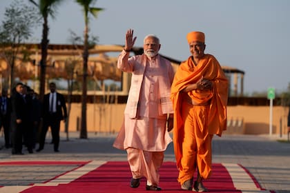 El primer ministro indio Narendra Modi, izquierda, saluda al caminar con el sacerdote hindú Brahmaviharidas Swami al arribar a la ceremonia de apertura del primer templo hindú de piedra construido en el Oriente Medio