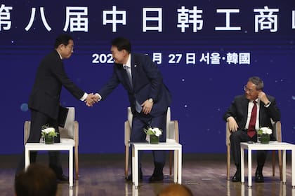 El primer ministro japonés, Fumio Kishida, le da la mano al presidente surcoreano, Yoon Suk Yeol, mientras el primer ministro chino, Li Qiang, mira mientras asisten a una reunión de negocios en la Cámara de Comercio e Industria de Corea en Seúl, Corea del Sur