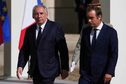 El primer ministro saliente Francois Bayrou (izq) y el entrante Sebastien Lecornu