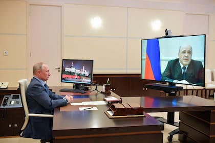 El primer ministro, Mijaíl Mishustin, (en la pantalla) junto a Vladímir Putin por videoconferencia.