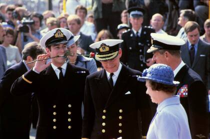 El príncipe Andrés sostiene una rosa cn su boca delante de sus padres, la Reina Isabel II y el Príncipe Felipe, en su regreso de las Malvinas a bordo del HMS Invincible; detrás de él está la princesa Ana