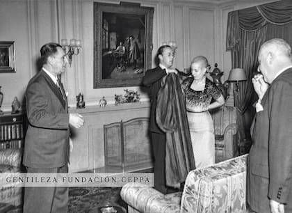 El príncipe consorte Bernardo de Holanda, marido de la reina Juliana, ayuda a Eva a ponerse su abrigo en una cena íntima en la residencia presidencial.