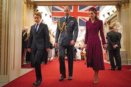 El príncipe George junto a sus padres, los príncipes de Gales, a su llegada a la recepción para los combatientes de la Segunda Guerra Mundial. Para esta ocasión, Kate eligió un vestido-abrigo con solapas y botonadura cruzada de Emilia Wickstead –en su guardarropa lo tiene en tres colores diferentes–, tocado a juego (recuerda los pill-box que usaba Jackie Kennedy), y lo complementó con pendientes y un colgante de brillantes y rubíes.