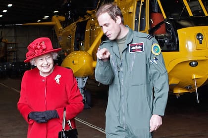 El príncipe Guillermo muestra a su abuela, la reina Isabel II de Inglaterra, el hangar donde se guarda el helicóptero en el que realiza las prácticas como piloto de búsqueda y rescate el 1 de abril de 2011 en el cuartel de la Fuerza Aérea británica en Holyhead, Anglesey, Reino Unido