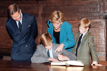 El príncipe William firma el tradicional libro de entrada acompañado por sus padres y su hermano Harry, en 1995.