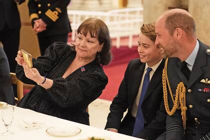El príncipe William y su hijo George posan para una selfie con una de las invitadas a tomar el té en Buckingham.