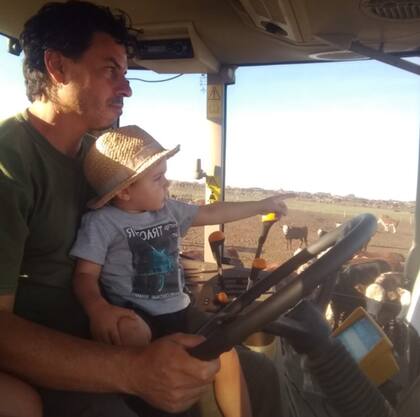 El productor Patricio Crivelli con su hijo en su tractor, en plena faena en su feedlot en San Pedro, provincia de Buenos Aires