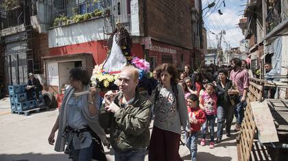 El público participa de una procesión religiosa en la calle, como parte de la obra