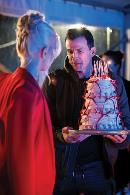 El recordman le acerca a su hija la torta de tres pisos rosa, decorada con cintas rojas, de Beka Pastry