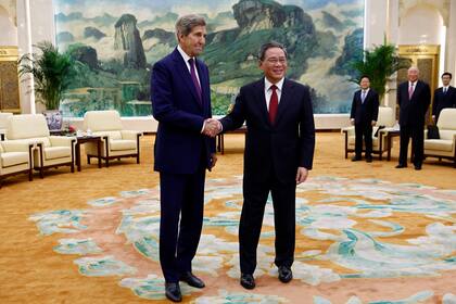 El representante especial de clima John Kerry, a la izquierda, y el primer ministro de China, Li Qiang, se estrechan la mano antes de una reunión en el Gran Salón del Pueblo en Beijing el martes 18 de julio de 2023. (Florence Lo/Pool Foto via AP)