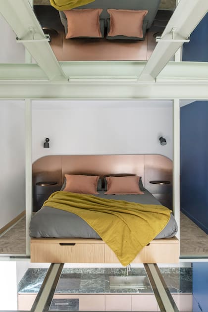 El respaldo de la cama (StudioTamat) retoma el degradé de los muebles de cocina, que se ven a través del piso transparente.