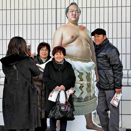 Los fanáticos se toman fotos con una gigantografía del gran campeón en el estadio de Ryogoku Kokugikan