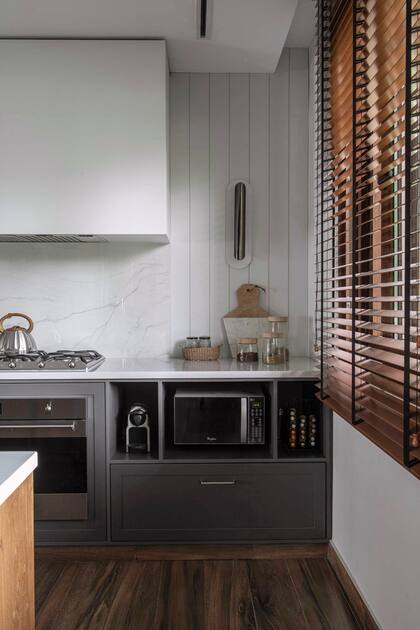 El revestimiento de madera ranurada y laqueada solo se interrumpe en la alzada, por una cuestión de precaución ante la proximidad del fuego. Aplique de luz (La Feliz).