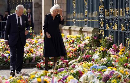 El rey británico Carlos III y la reina consorte Camilla observan las flores y los homenajes dejados en honor a su difunta madre, la reina Isabel II, a su llegada al castillo de Hillsborough, en Belfast, el 13 de septiembre de 2022, durante su visita a Irlanda del Norte.