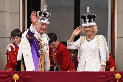 El Rey Carlos III de Gran Bretaña, con la Corona Imperial de Estado, y la Reina Camilla, con una versión modificada de la Corona de la Reina María, saludan desde el balcón del Palacio de Buckingham tras ver el sobrevuelo de la Royal Air Force en el centro de Londres el 6 de mayo de 2023, después de sus coronaciones. (Foto de Oli SCARFF / AFP)
