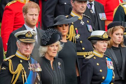 El rey Carlos III de Gran Bretaña junto a Camilla; la princesa Ana, la princesa Beatriz, Meghan, la duquesa de Sussex y el príncipe Harry observan cómo se coloca el ataúd de la reina Isabel II en el coche fúnebre después del funeral de estado en la Abadía de Westminster