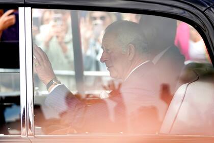 El rey Carlos III saluda a la multitud desde su auto
