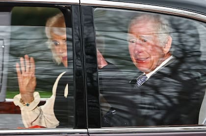 El rey Carlos III y la reina consorte Camilla saludan mientras salen en auto desde Clarence House en Londres.