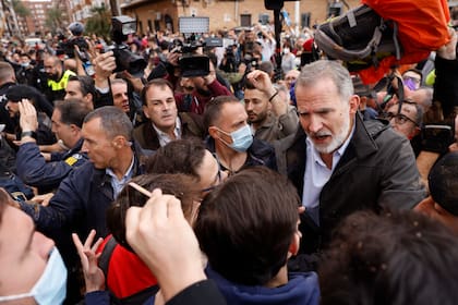 El rey Felipe habla con vecinos afectados por la riada, durante su visita a Paiporta este domingo. Gritos de 'fuera', así como lanzamiento de barro, están recibiendo a la comitiva de los reyes de España, el presidente del Gobierno, Pedro Sánchez, y el president de la Generalitat, Carlos Mazón, a su llegada al centro de Paiporta.