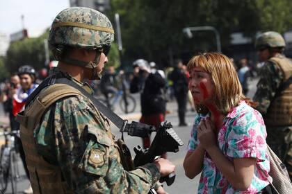 Una joven se para frente a un carabinero en medio de las protestas