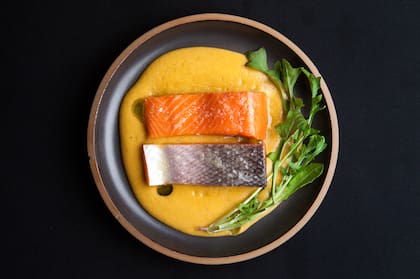 El salmón cocido apenas a 42 °C sale emulsión de zanahoria, papa y menta, con rúcula.