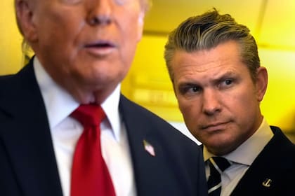 El secretario de Defensa de Estados Unidos, Pete Hegseth, escucha mientras el presidente Donald Trump habla con periodistas; buscan realizarles un juicio político (AP Foto/Mark Schiefelbein)