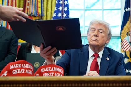 El secretario de personal de la Casa Blanca Will Scharf entrega al presidente Donald Trump una orden ejecutiva para que la firme, en la Oficina Oval de la Casa Blanca, el miércoles 23 de abril de 2025, en Washington.