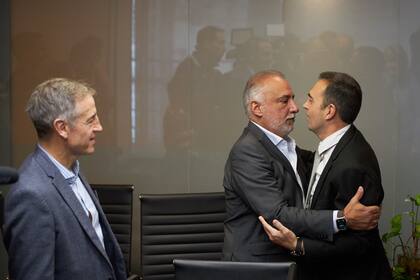 El secretario de Trabajo, Julio Cordero, se abraza con el sindicalista mercantil Carlos Pérez ante la atenta mirada de Jorge Sola