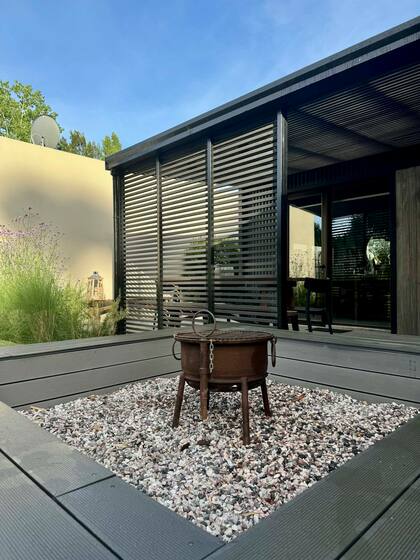 El sector del fogonero en el jardín cuenta un gran banco revestido con el mismo deck que la galería para crear “un efecto de continuidad”.
