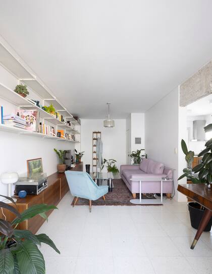 El sector del living acompañado por una extensa biblioteca metálica modular. Perchero de madera maciza (Dralas Deco).