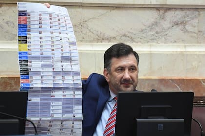 El senador Edgardo Kueider muestra una boleta única de papel bajo el modelo de Córdoba