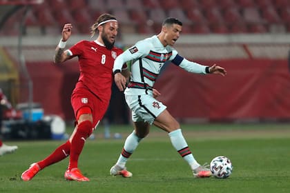 El serbio Nemanja Gudelj y el portugués Cristiano Ronaldo luchan por el balón durante el partido de clasificación del grupo A para la Copa Mundial 2022 entre Serbia y Portugal en el estadio Rajko Mitic en Belgrado, Serbia, este sábado.