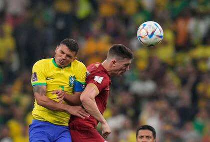 El serbio Dusan Vlahovic (derecha) y el brasileño Thiago Silva saltan por un balón en un partido del Grupo G del Mundial